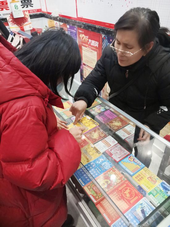 09AA  体彩店里传递暖流。看这位销售员阿姨的眼神和手势里，“写”满了耐心、热心、关心。如此“有心”的彩站，怎能不受欢迎？.jpg